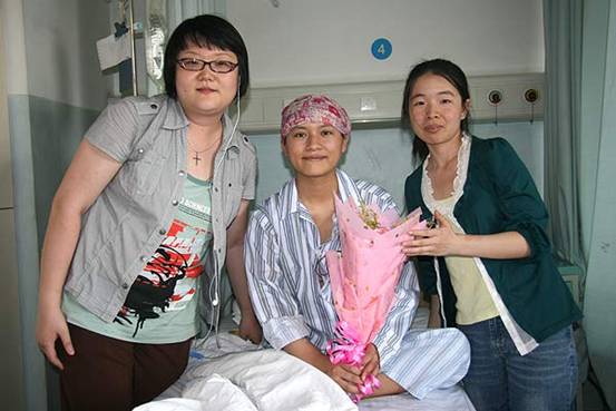 Feng Juan (M) receives flowers from Li Wei (L) and Wang Chunxia (R), work staff of Beijing Enable Disability Studies Institute in Beijing Cancer Hospital on June 8. [CnDG by Jiao Meng]