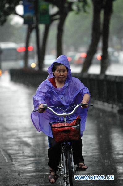 A cyclist moves in the rain on a street in Hangzhou, capital of east China&apos;s Zhejiang Province, June 9, 2011. Multiple places in Zhejiang witnessed rainfall on Thursday, which marks the beginning of Meiyu season. Meiyu season is a month-long period in which rain falls continuously for most time. [Xinhua]