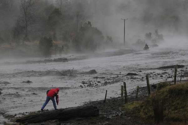 Steam rises from the Nilhue River, fed by unusually warm water from the hot flanks of an erupting volcano from the Puyehue-Cordon Caulle volcanic chain, as a resident inspects the river water near Lago Ranco town June 9, 2011. A thick cloud of ash from the Chilean volcano brought airports to a halt in Argentina and neighboring Uruguay on Thursday, forcing airlines to cancel dozens of flights, airport officials said. [China Daily/Agencies]