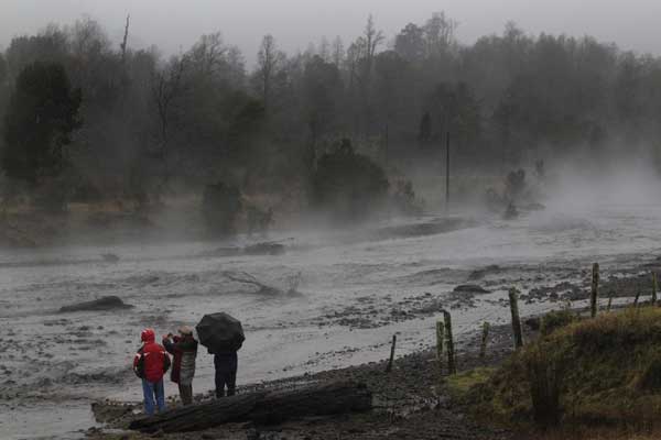 Residents watch as steam rises from the Nilhue River, fed by unusually warm water from the hot flanks of an erupting volcano from the Puyehue-Cordon Caulle volcanic chain, near Lago Ranco town June 9, 2011. [China Daily/Agencies]