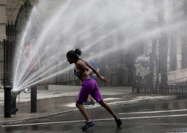 A child plays under the spray of a fire hydrant in Riverside, Manhattan, as temperatures soared in New York June 9, 2011. Temperatures soared over 90 degrees in New York as a heat wave baked a large part of the US. [China Daily/Agencies] 