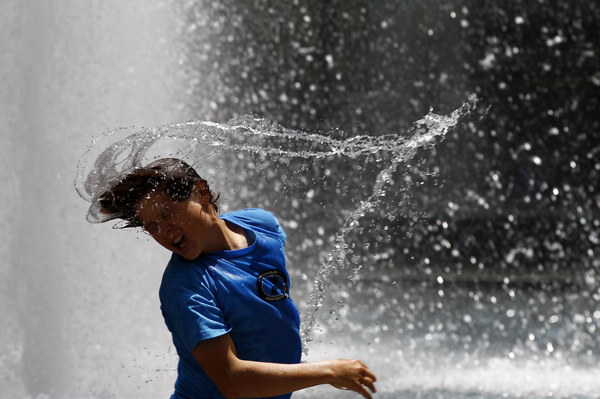 Brad Casale shakes water off his hair after dunking his head in the water fountain at the Hirshhorn Museum and Sculpture Garden in Washington June 9, 2011. Temperatures in the area are expected to exceed 100 degrees Fahrenheit (38 degrees Celsius). [China Daily/Agencies]