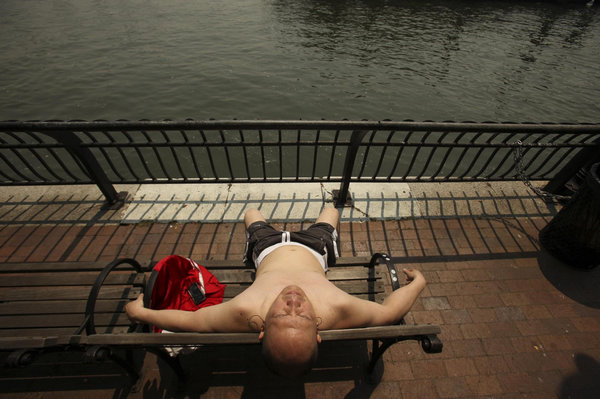 A man catches some sun along Manhattan&apos;s East River on a day that temperatures soared in New York June 9, 2011. [China Daily/Agencies]