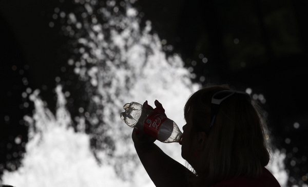 A woman is silhouetted against a water fountain as she takes a drink at the Hirshhorn Museum and Sculpture Garden in Washington June 9, 2011. Temperatures in the area are expected to exceed 100 degrees Fahrenheit (38 degrees Celsius). [China Daily/Agencies]