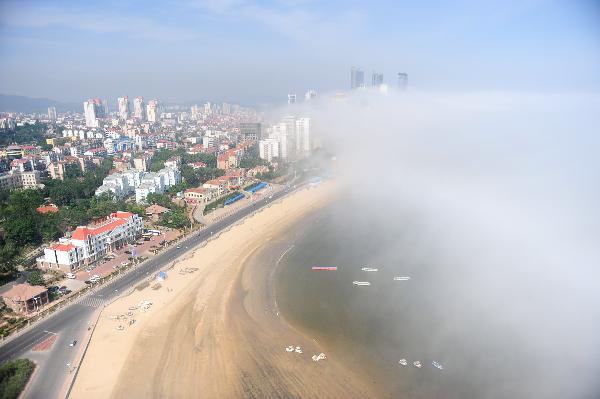 Photo taken on June 9, 2011 shows the city beach hovered by silk-like advection fog in Yantai, east China's Shandong Province. [Xinhua/Chu Yang] 