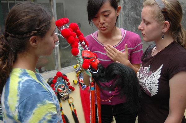 Foreign students studying in Liaocheng University listen to an introduction of a Peking Opera mask in Liaocheng, east China's Shandong Province, June 9, 2011. 