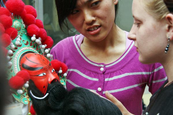 Katherine Jones, an American student studying in Liaocheng University looks at a Peking Opera mask in Liaocheng, east China's Shandong Province, June 9, 2011.
