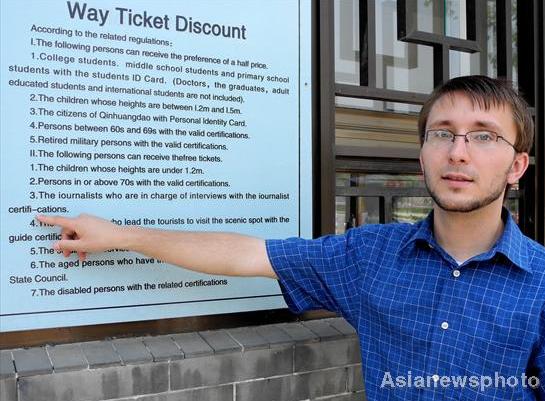 An American English teacher in Qinhuangdao points to an inaccurate translation outside the ticket office of a scenic spot in North China's Hebei province, June 9, 2011. 