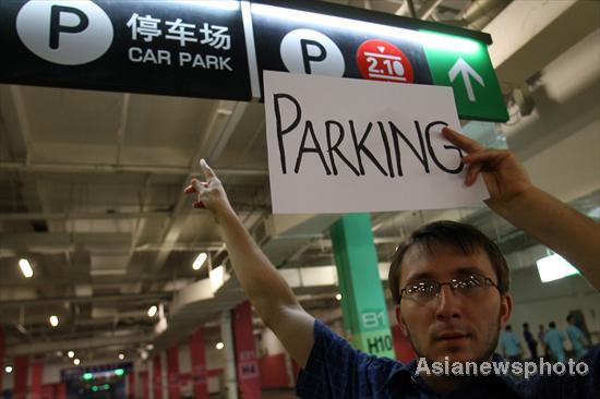 An English teacher in Qinhuangdao shows his American translation of a sign for a parking lot in North China's Hebei province, June 9, 2011. 
