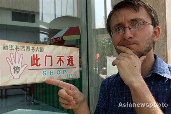 Paul, a native English speaker from the United States, points to a puzzling translation outside a bookstore in Qinhuangdao, North China's Hebei province, June 9, 2011.