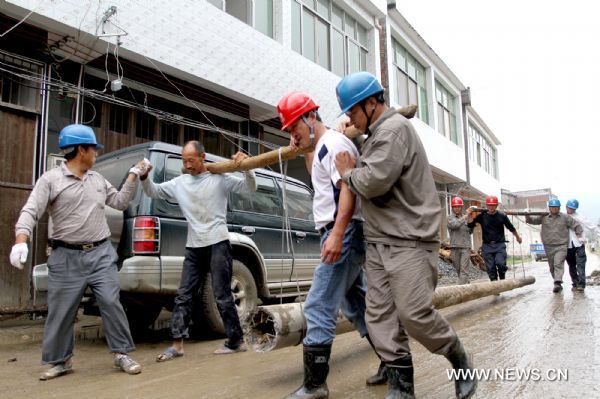 Electricians carry a wire pole as they fulfill a repair task in Taoshu Village of Xiushui County, east China's Jiangxi Province, June 11, 2011. Rain-triggered flood hit the county on Friday. Flood-relief works have been carried out in Xiushui to reduce the economic losses. [He Guang/Xinhua]