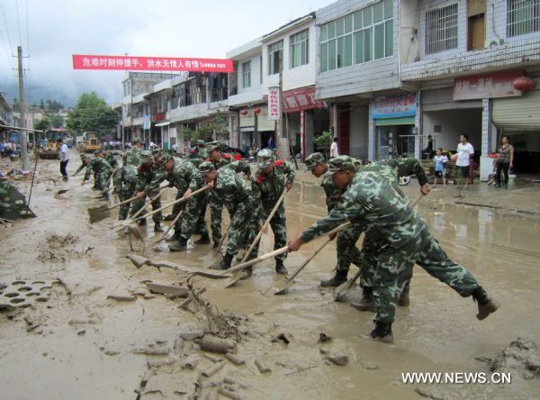 Armed soldiers clear silt in Taoshu Village of Xiushui County, east China's Jiangxi Province, June 11, 2011. Rain-triggered flood hit the county on Friday. Flood-relief works have been carried out in Xiushui to reduce the economic losses. [Xia Xiaojun/Xinhua]