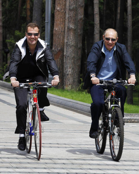 Russian President Dmitry Medvedev (L) and Prime Minister Vladimir Putin ride bicycles during an informal meeting at the presidential residence at Gorki outside Moscow June 11, 2011. [Photo/Agenies]