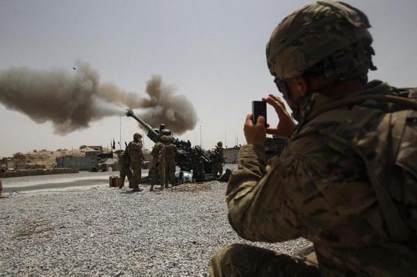 A US Army soldier from the 2nd Platoon, B battery 2-8 field artillery, takes a picture of a howitzer artillery piece being fired at Seprwan Ghar Forward fire base in Panjwai district, Kandahar province in southern Afghanistan, June 12, 2011. [China Daily/Agencies]