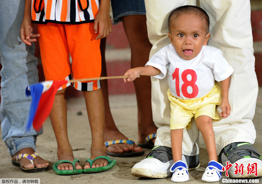 Junrey Balawing holds a miniature Philippine flag as he and his family pose for photographers in Sindangan, Zamboanga del Norte in southern Philippines June 11, 2011. [Photo/Chinanews.com.cn]