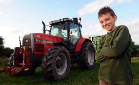 Nice wheels: Tom Phillips, 10, with the tractor he used to save his father Andrew's life when he was attacked by a raging bull