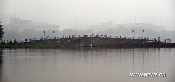 Visitors tour the West Lake in rain, in Hangzhou, capital of east China's Zhejiang Province, June 11, 2011. The local observatory of Hangzhou issued orange warning signal of rainstorm on Saturday and announced the start of a month-long rainy season since June 10. [Xinhua/Xu Yu]