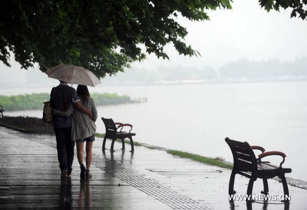 Visitors tour the West Lake in rain, in Hangzhou, capital of east China's Zhejiang Province, June 11, 2011. The local observatory of Hangzhou issued orange warning signal of rainstorm on Saturday and announced the start of a month-long rainy season since June 10. [Xinhua/Xu Yu] 