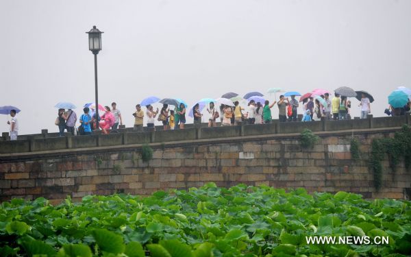 Visitors tour the West Lake in rain, in Hangzhou, capital of east China's Zhejiang Province, June 11, 2011. The local observatory of Hangzhou issued orange warning signal of rainstorm on Saturday and announced the start of a month-long rainy season since June 10. [Xinhua/Xu Yu] 