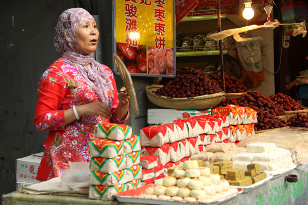 AMuslim woman sells snacks behind her stall along the Muslim Street. [Photo:CRIENGLISH.com]