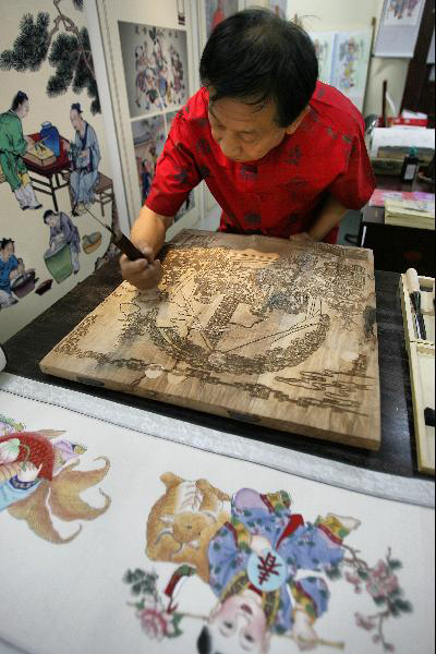 Huo Qingshun, successor of Yangliuqing New Year Paintings, makes New Year Painting in an exhibition of Chinese classics and intangible culture heritages in the National Library of China in Beijing, capital of China, June 8, 2011. The exhibition showcases about 200 historical documents about China's intangible heritages and many heritage successors are invited to show their skills on the spot. [Photo/Xinhua/Zhao Bing]