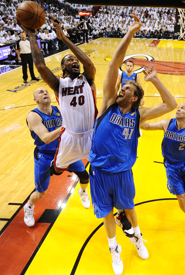 Udonis Haslem (L) of Miami Heat shoots before Dirk Nowtizki (R) of Dallas Mavericks before the Mavericks won Game 6 to win the NBA Finals 4-2, at the AmericanAirlines Arena in Miami, Florida on June 12, 2011. [Source: Sina.com]
