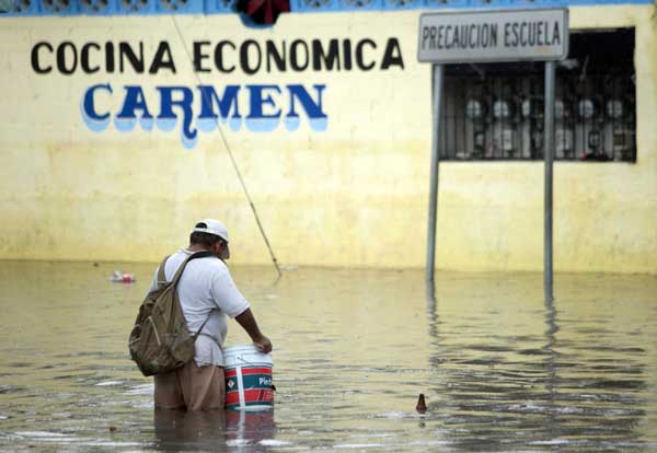 A man collect trash in a flooded street in Cancun, June 13, 2011. A heavy rain which lasted three hours caused several streets to flood in parts of Cancun, Mexico.[China Daily/Agencies]