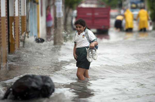 A girl reacts as she crosses a flooded street in Cancun, June 13, 2011.[China Daily/Agencies]