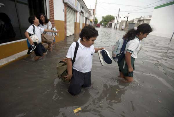 Children cross a flooded street in Cancun, June 13, 2011. [China Daily/Agencies]