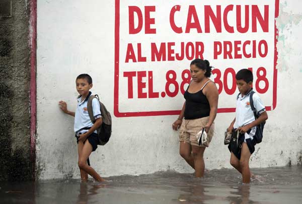 Two children and a woman cross a flooded street in Cancun, June 13, 2011. [China Daily/Agencies]