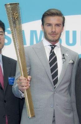 British soccer player David Beckham holds the Olympic torch at a Torchbearer nomination event in Canary Wharf, London, Monday, June 13, 2011.