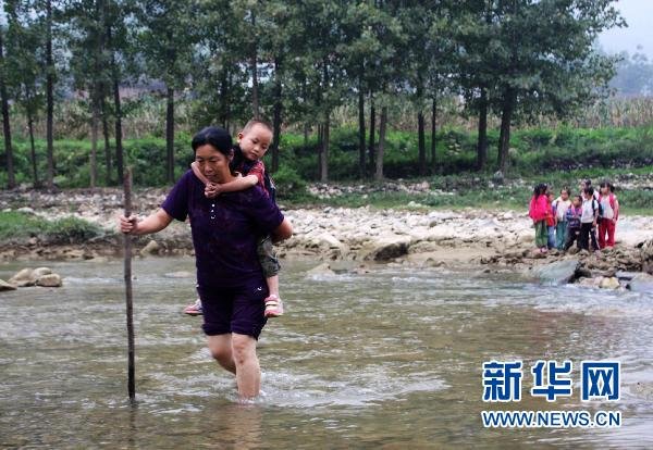 Zou Guifen is escorting her students across the river in front of the school. 
