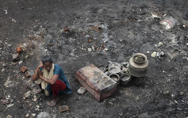 A resident sits besides her burnt belongings amid destroyed dwellings leveled by a fire at the Tondiapet slum in the southern Indian city of Chennai June 17, 2011. About 300 huts were gutted in the fire but no casualties were reported, a fire official said on Friday. The cause of the fire was unknown. [Xinhua/Reuters Photo]