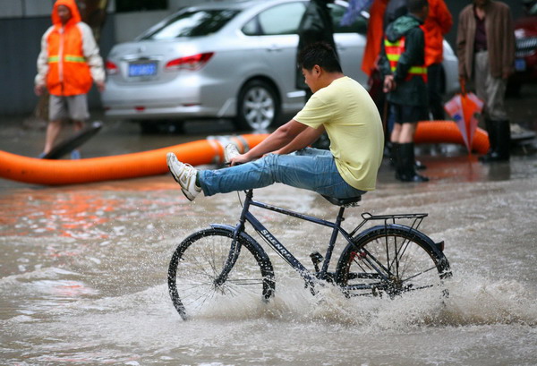 A bike rider wades through a flooded road in Nanjing, capital of East China Jiangsu province, June 18, 2011. A heavy downpour hit Nanjing on Friday evening, with a precipitation of more than 50mm. Major roads were immersed by floods, causing travel difficulties for motorists. Local meteorologists sent out an Orange Alert (middle level alert) forecasting possible continuing rain. [Photo/Xinhua] 