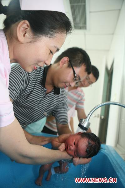 A freshmen father bathes his baby under the nurse's instruction in the No. 1 People's Hospital in Xiangyang, central China's Hubei Province, June 18, 2011. [Xinhua/Gong Bo] 
