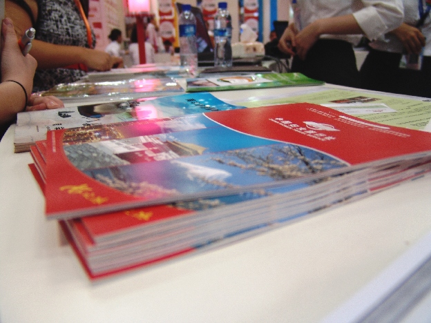 Brochures, women's travel—Booth visitors look at booklets and brochures at China Women Travel Service.[China.org.cn]