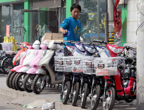 A salesman at an electric bicycle shop in Beijing cleans his new bikes outside the west gate of Tsinghua University. The ban on electric bicycles in Shenzhen might affect the industry.[China Daily]