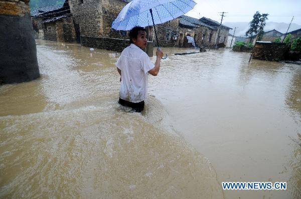 A villager makes his way forward in flood in Longtoushan Town of Dexing City, east China's Jiangxi Province, June 19, 2011.