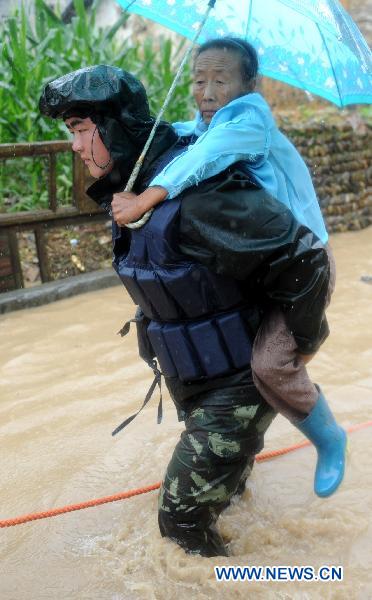 An armed policeman help evacuate a senior villager in Longtoushan Town of Dexing City, east China's Jiangxi Province, June 19, 2011. 