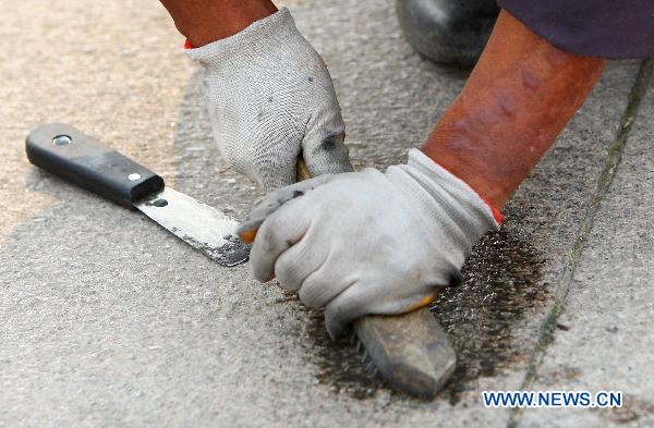 A worker cleans chewing gum on the tiles in Tian'anmen Square in Beijing, capital of China, June 19, 2011. 