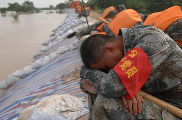 A PLA soldier takes a rest during dike reinforcement efforts in Lanxi city, East China's Zhejiang province, June 20, 2011. [Xinhua] 