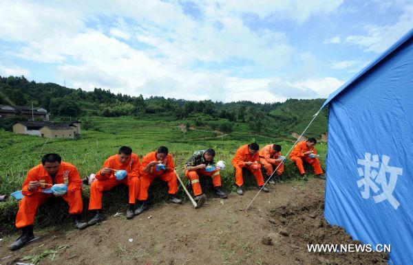 Rescuers have a meal next to makeshift tents after an earthquake in Tengchong County, southwest China's Yunnan Province, June 21, 2011. The 5.2-magnitude earthquake that hit Tengchong on Monday has left six people injured and caused significant economic losses, the Ministry of Civil Affairs said Tuesday. As of 3 p.m. Tuesday, the quake had affected 22,000 local residents and led to the emergency relocation of 2,168 people. The local government has allocated 7 million yuan to set up a disaster relief fund, as well as sent hundreds of tents, quilts and articles of clothing to the quake zone, according to the ministry. (Xinhua/Yang Zongyou) (hdt) 