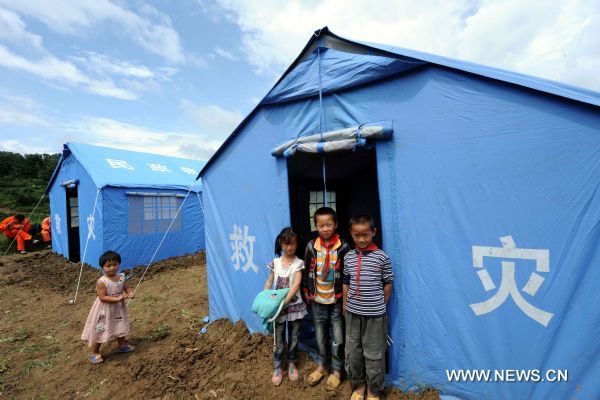 Displaced children stand next to makeshift tents after an earthquake in Tengchong County, southwest China's Yunnan Province, June 21, 2011. The 5.2-magnitude earthquake that hit Tengchong on Monday has left six people injured and caused significant economic losses, the Ministry of Civil Affairs said Tuesday. As of 3 p.m. Tuesday, the quake had affected 22,000 local residents and led to the emergency relocation of 2,168 people. The local government has allocated 7 million yuan to set up a disaster relief fund, as well as sent hundreds of tents, quilts and articles of clothing to the quake zone, according to the ministry. (Xinhua/Yang Zongyou) (hdt) 