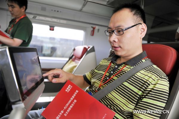 A media reporter touches a multimedia info terminal on a bullet train on the Beijing-Shanghai high-speed railway in Jinan, capital of east China's Shandong Province, June 21, 2011. Media reporters experienced a trial operation on the Beijing-Shanghai high-speed railway on Tuesday. It takes a 300-kph bullet train one hour and 32 minutes from Jinan West Railway Station to Beijing South Railway Station, 2 hours shorter than the current high-speed trains. (Xinhua/Zhu Zheng) (zgp) 