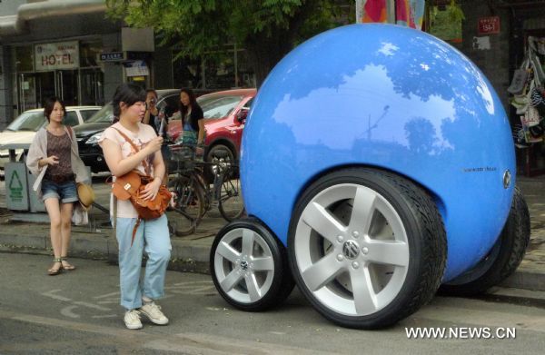 A woman takes photo of a concept car of Volkswagen's People's Car Project on Gulou East Street in Beijing, capital of China, June 21, 2011. Volkswagen initiated the People's Car Project in China recently to eastablish a platform for the public to participate in designing their own future automobiles. (Xinhua/Zhao Bing) (zgp) 