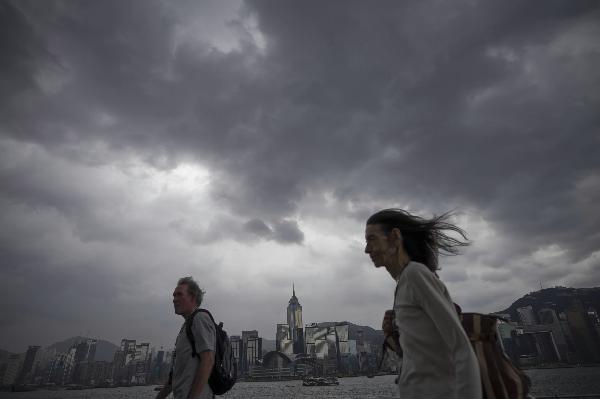 Tourists walk at Tsim Sha Tsui, an urban area in Hong Kong, south China, June 21, 2011. Hong Kong Observatory issued a warning of tropical storm on Tuesday. It is predicted that strong wind and heavy rain will hit the city in the next few days.