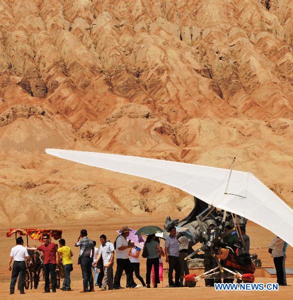 Tourists rest under wings of an aerocraft, sheltering from the sunshine, in the Flaming Mountain scenic area of Turpan, a basined area of northwest China's Xinjiang Uygur Autonomous Region, June 22, 2011. In spite of the earth surface's temperature reaching to nearly 72 degrees Celsius, many tourists came here to experience the burning heat. (Xinhua/Jiang Xiaoming) 