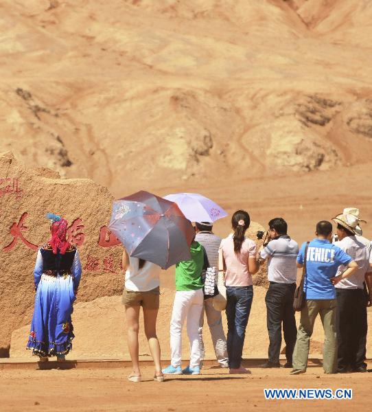 Tourists visit the Flaming Mountain scenic area of Turpan, a basined area of northwest China's Xinjiang Uygur Autonomous Region, June 22, 2011. [Xinhua/Jiang Xiaoming] 