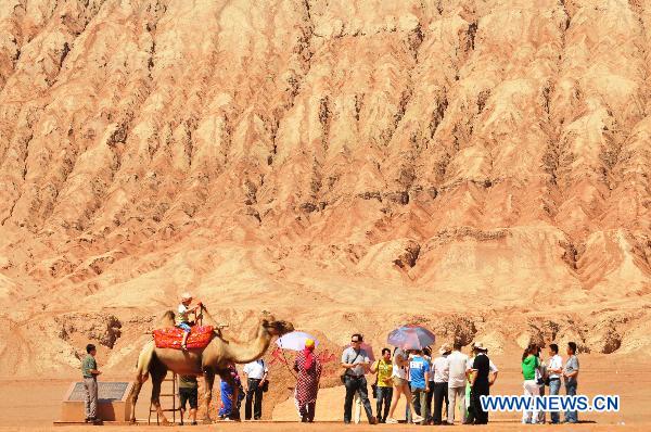 Tourists visit the Flaming Mountain scenic area of Turpan, a basined area of northwest China's Xinjiang Uygur Autonomous Region, June 22, 2011. [Xinhua/Jiang Xiaoming] 