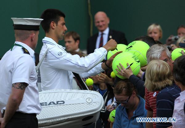 Novak Djokovic (2nd L) of Serbia signs for spectators after his first round match against Jeremy Chardy at the 2011 Wimbledon tennis championships in London, Britain, June 21, 2011. Novak Djokovic won 3-0. (Xinhua/Tang Shi) 